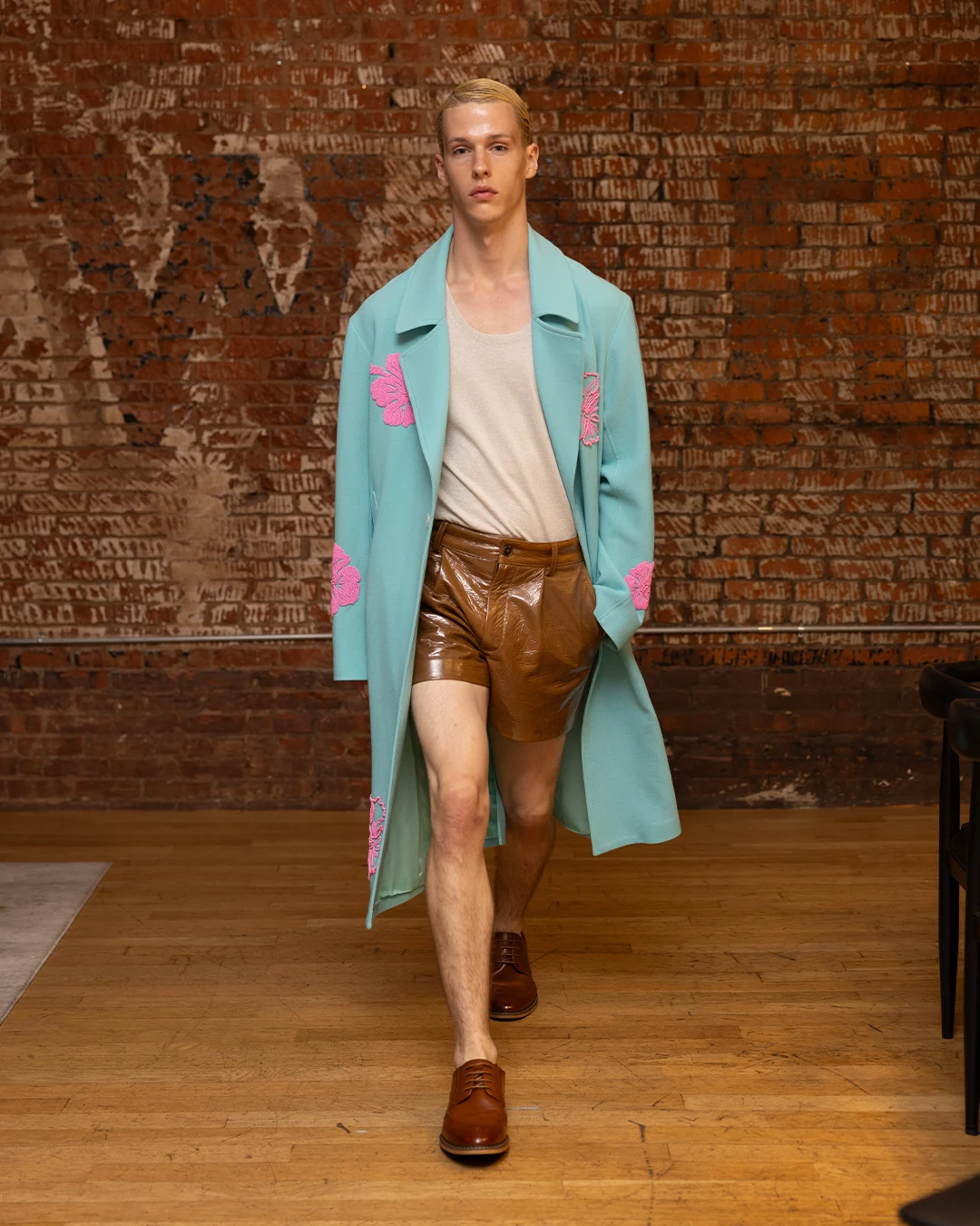 Runway shot of a model wearing a Hold NYC jacket adorned with hand-beaded Hawaiian floral appliqués.