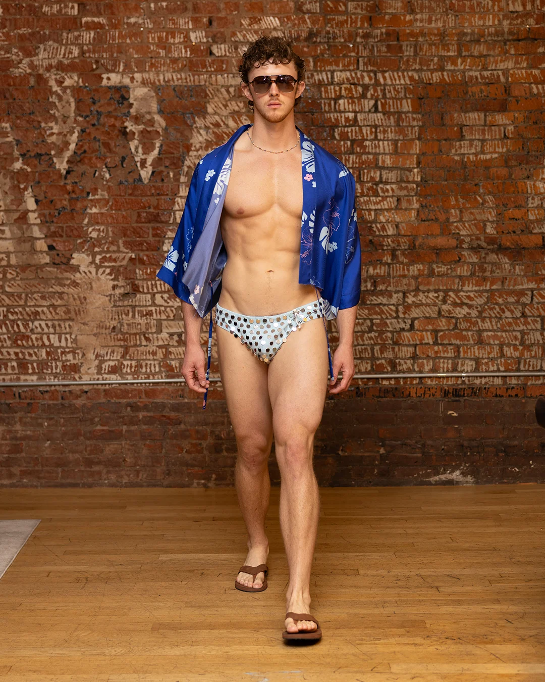 Runway shot of a model wearing Hold NYC swim trunks with intricate hand-applied bead embellishments.