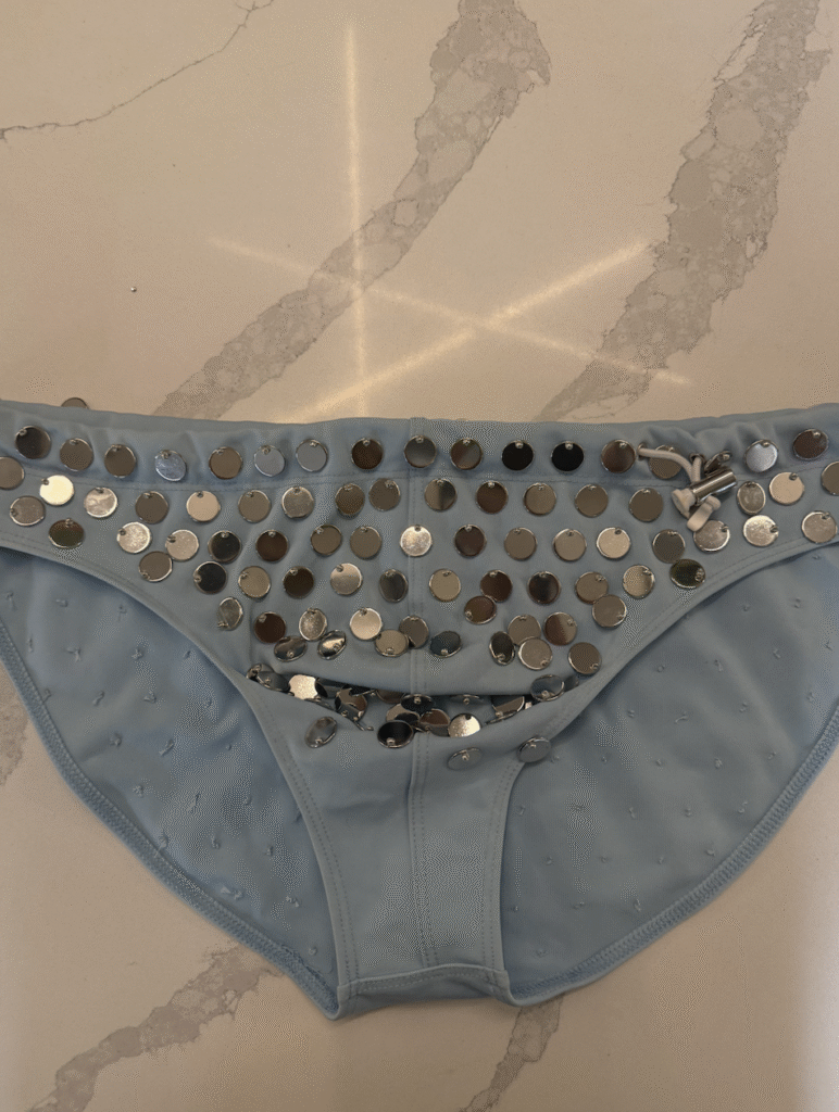 Runway shot of a model wearing Hold NYC swim trunks with intricate hand-applied bead embellishments.