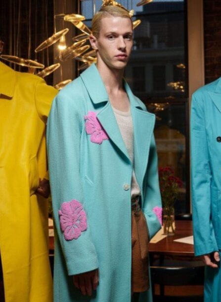 Runway shot of a model wearing a Hold NYC jacket adorned with hand-beaded Hawaiian floral appliqués.