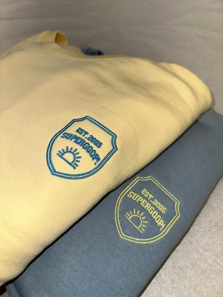 Close-up of a Supergoop! sweater embroidered with custom designs, part of a college tour giveaway.
