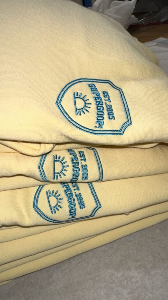 Close-up of a Supergoop! sweater embroidered with custom designs, part of a college tour giveaway.
