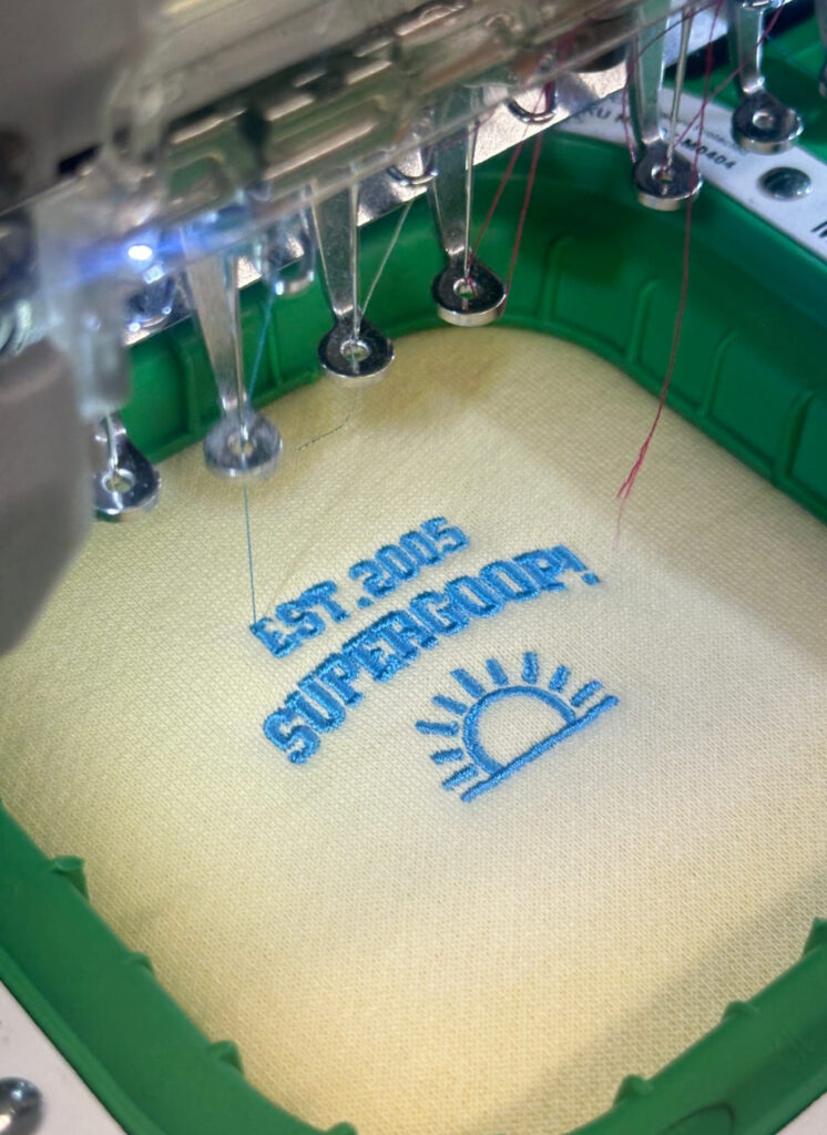 Close-up of a Supergoop! sweater embroidered with custom designs, part of a college tour giveaway.