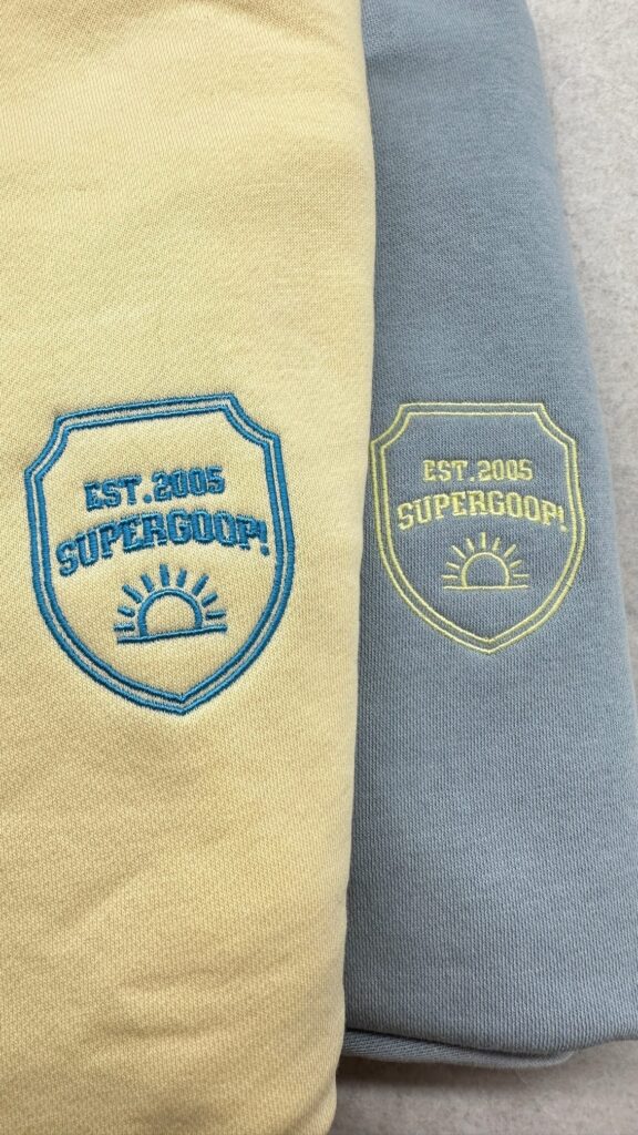 Close-up of a Supergoop! sweater embroidered with custom designs, part of a college tour giveaway.