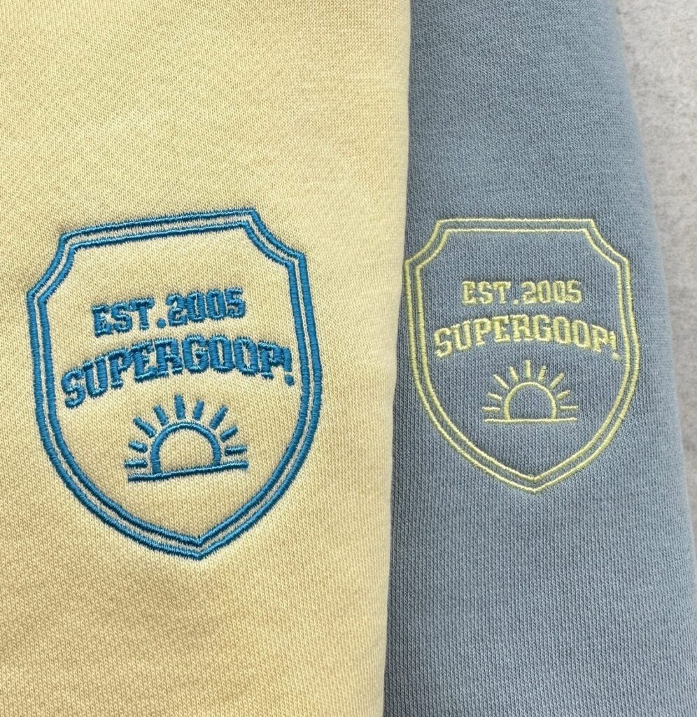 Close-up of a Supergoop! sweater embroidered with custom designs, part of a college tour giveaway.