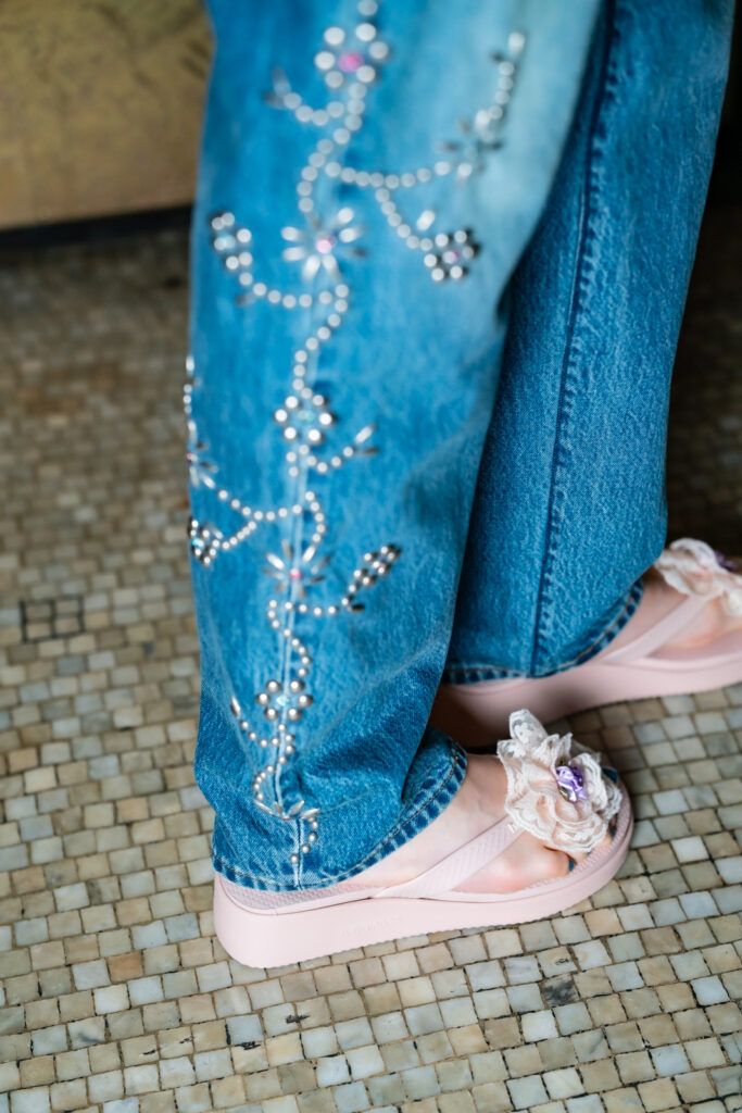Runway shot of a model wearing an Anna Sui SS26 look featuring delicate shirring and hand-applied embellishments, creating a romantic, textured silhouette.