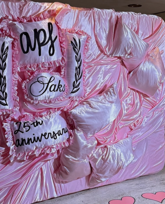 Custom chain-stitched pillow cases arranged on a backdrop for the APF Gala photo-op.