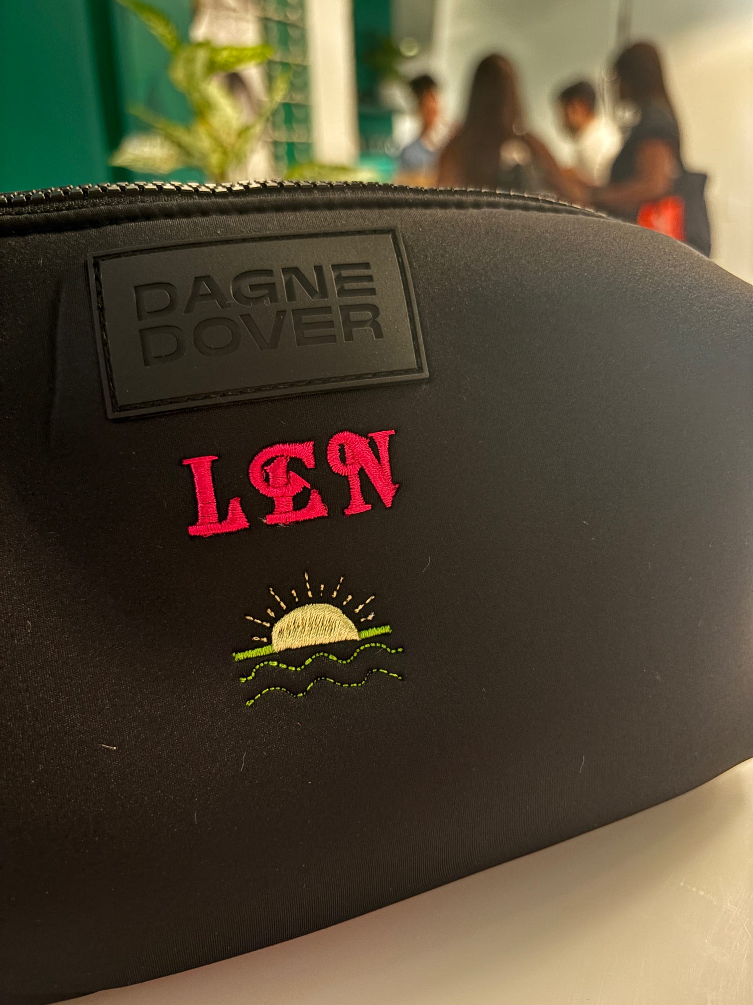Guests having their Dagne Dover pouches custom embroidered live at the Taboola event.