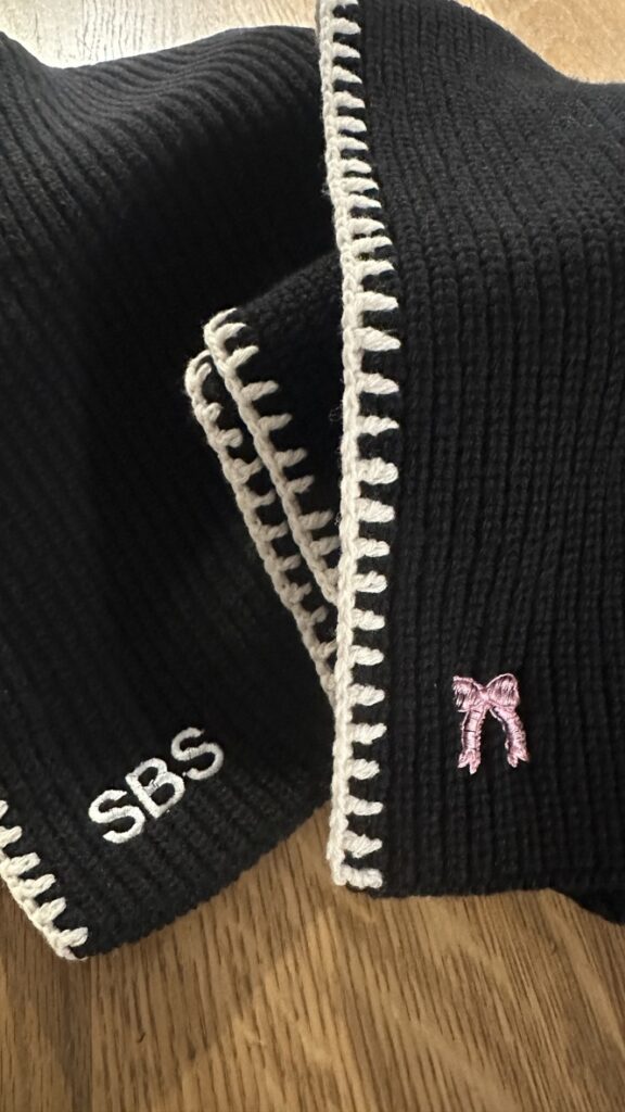 Custom embroidered scarves and hats displayed at the TJ Maxx x Marshalls holiday event.