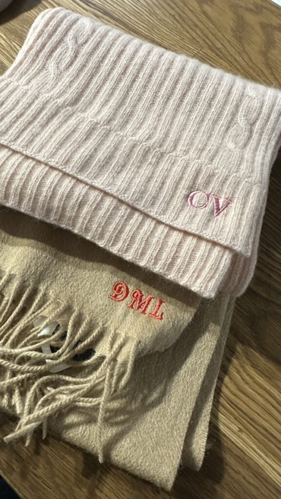 Custom embroidered scarves and hats displayed at the TJ Maxx x Marshalls holiday event.