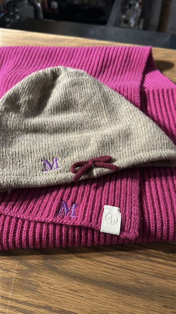 Custom embroidered scarves and hats displayed at the TJ Maxx x Marshalls holiday event.