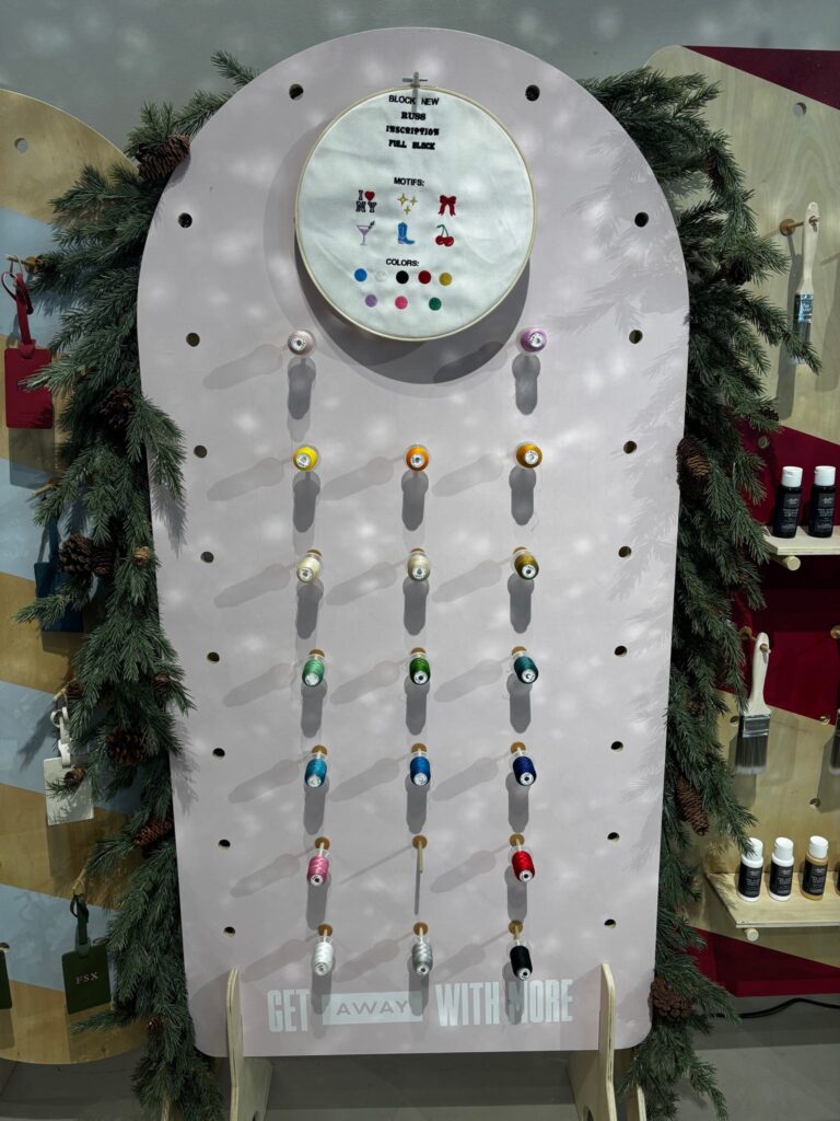 NYES embroidery color board showcasing holiday motifs—bows, stars, cherries, cocktails—and full thread color selections available for AWAY product personalization.