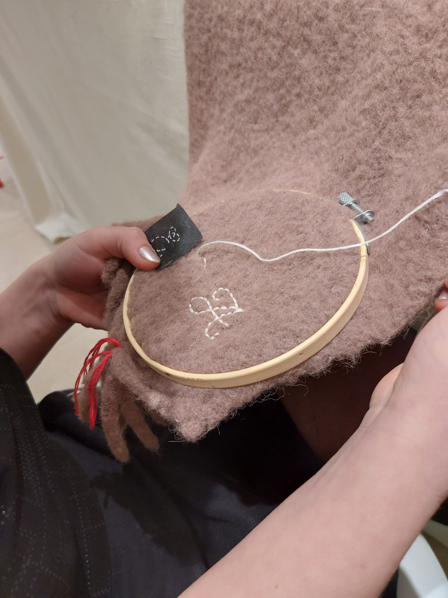 Hand-embroidered white initials stitched onto a beige cashmere scarf with hand-tied fringe detailing
