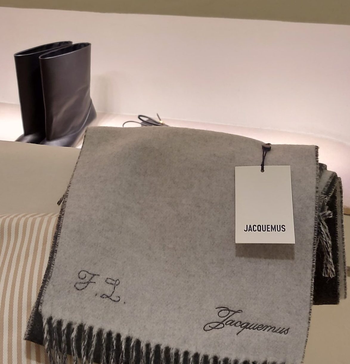 Hand-embroidered black initials stitched onto a beige cashmere scarf with hand-tied fringe detailing