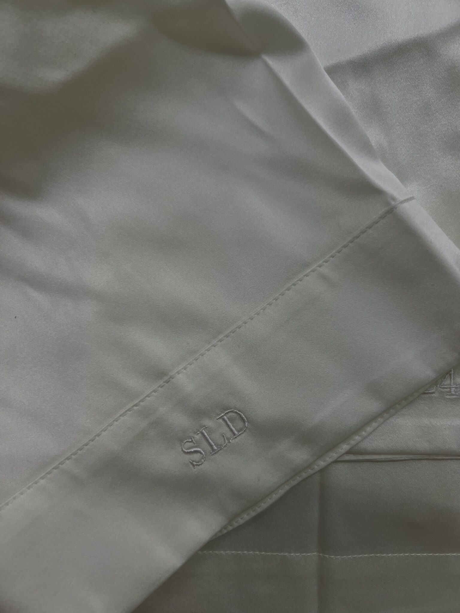 Close-up of custom white-on-white embroidered initials “SLD” on a bridal garment cuff