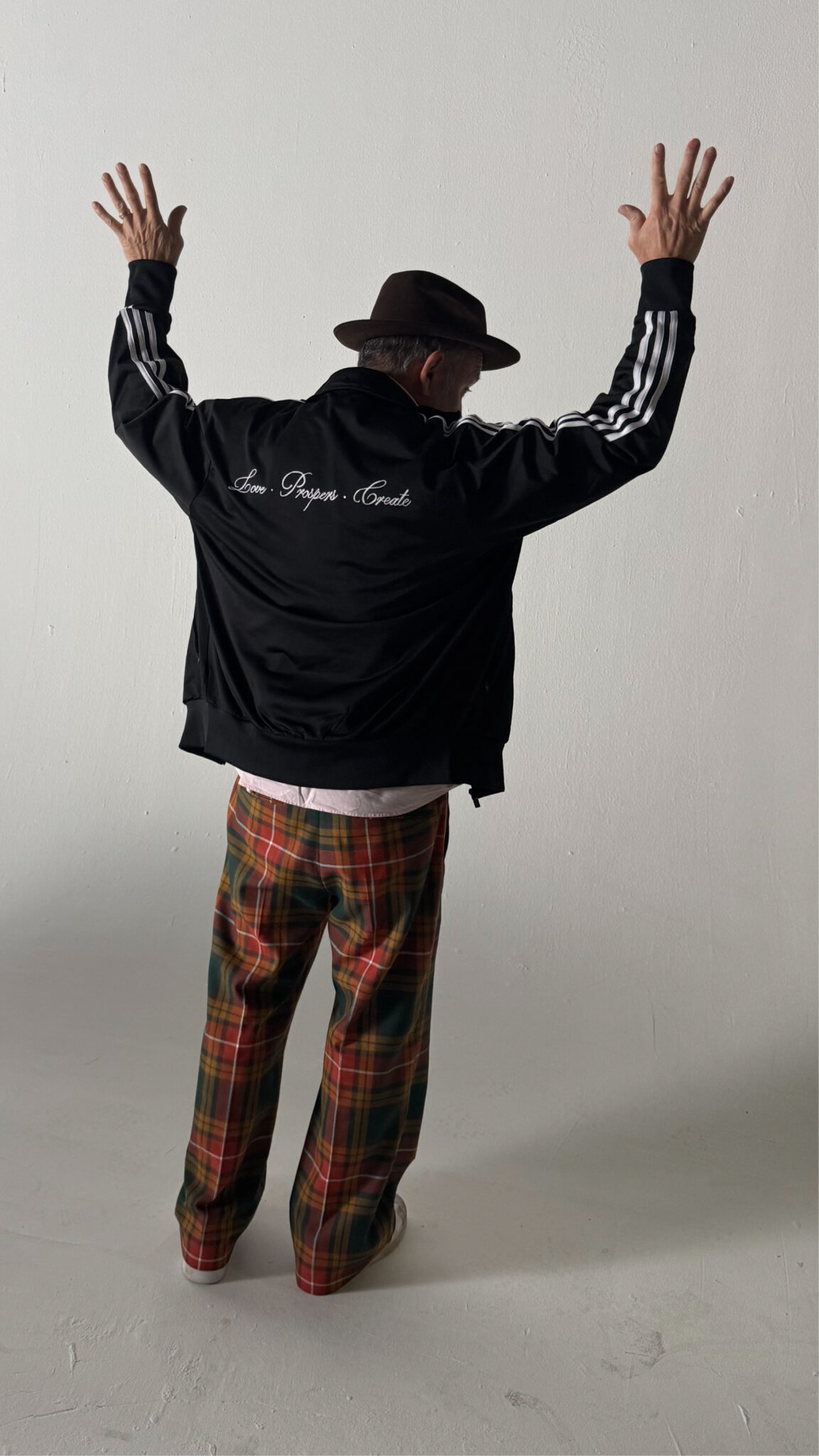 Man wearing a black track jacket with chain stitched embroidery on the chest