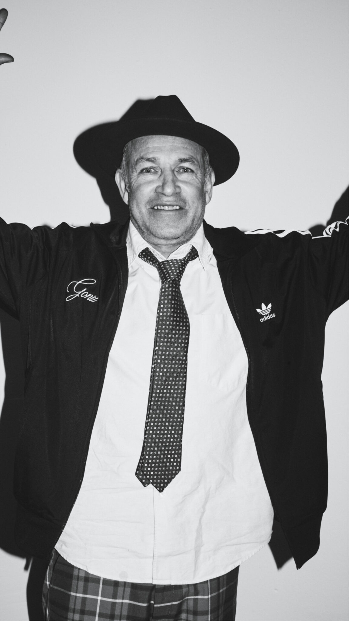 Man wearing a black track jacket with chain stitched embroidery on the chest
