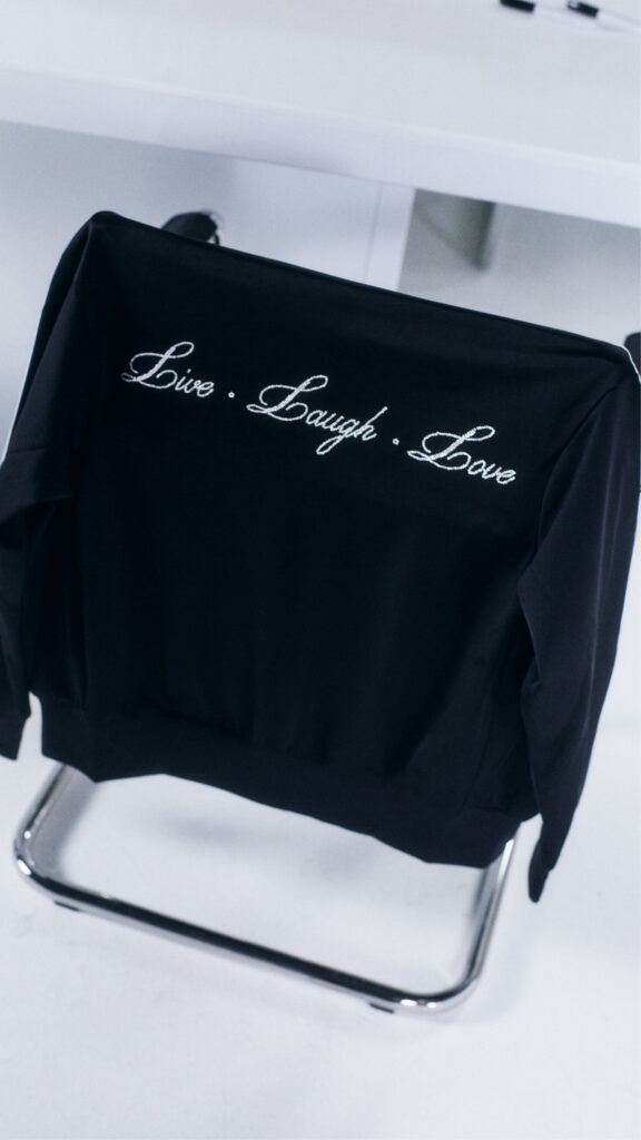 Close-up of hot fix crystal lettering applied to a black athletic jacket