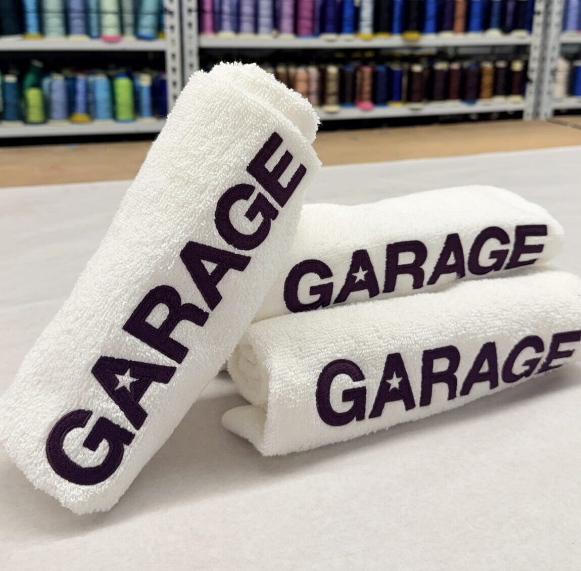 Stacked white towels featuring embroidered Garage logos
