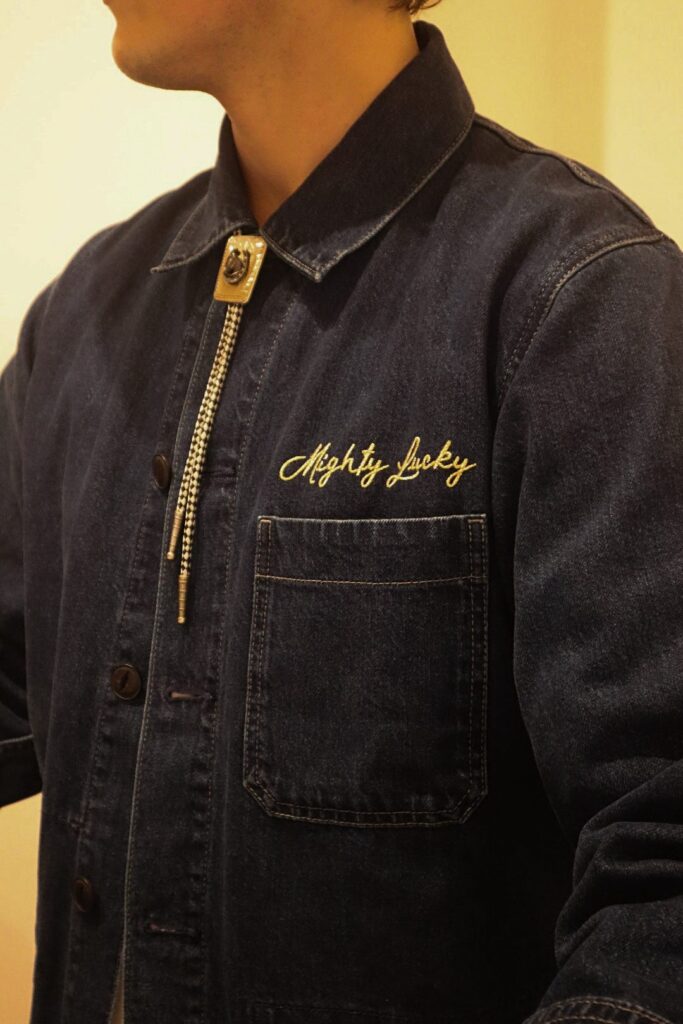 Embroidered Mighty Lucky denim jacket displayed in-store