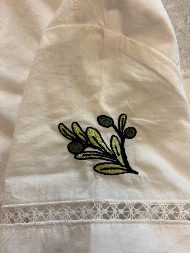 Small embroidered motif stitched onto white J.Crew garment near placket