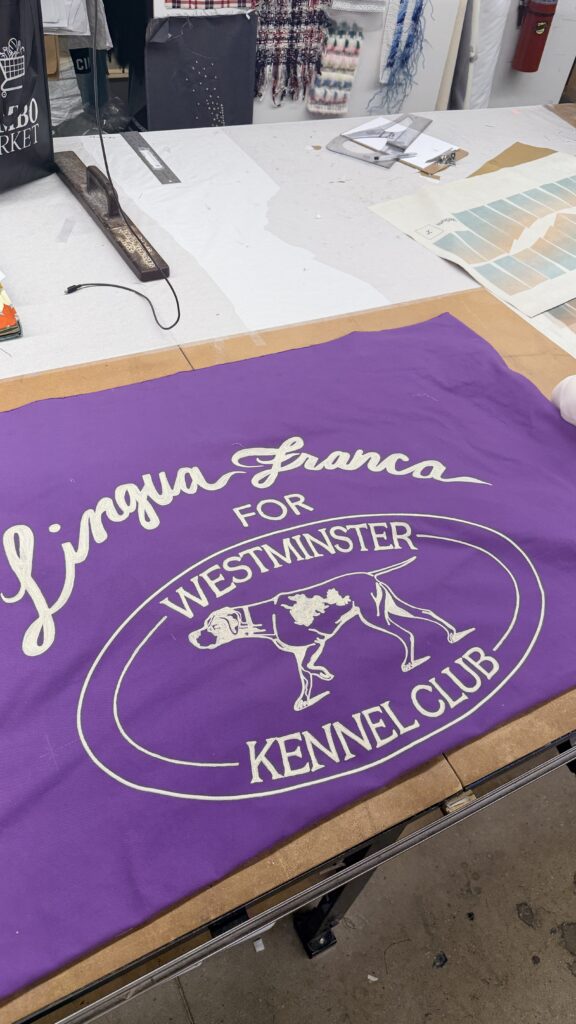 Chain stitch embroidered banner for Lingua Franca featuring white lettering and dog illustration on purple fabric for the Westminster Kennel Club Dog Show