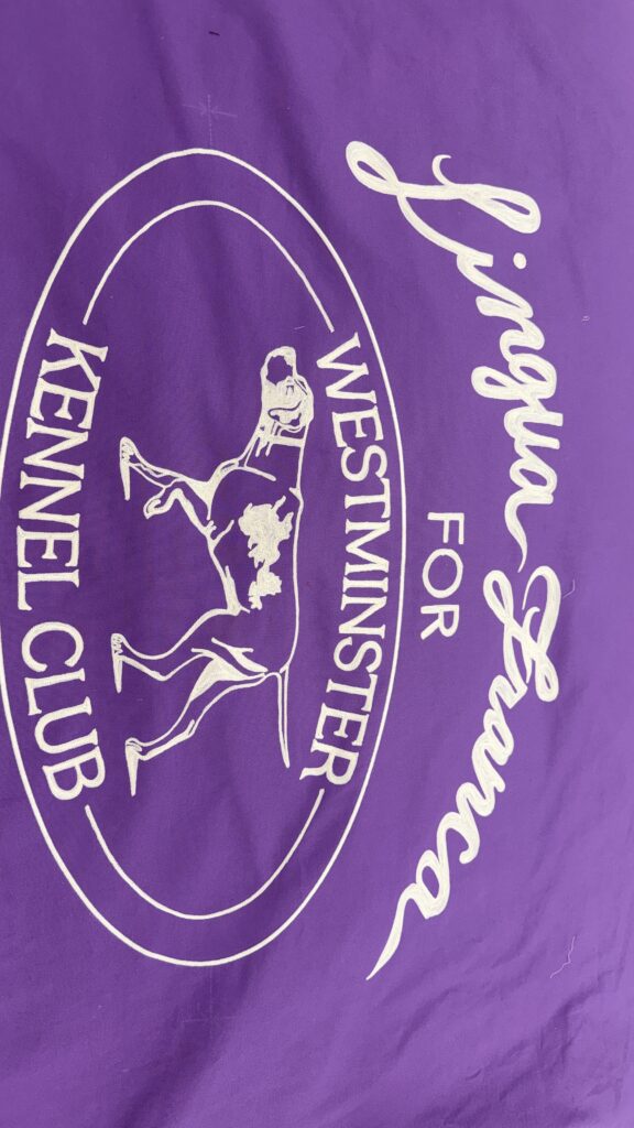 Chain stitch embroidered banner for Lingua Franca featuring white lettering and dog illustration on purple fabric for the Westminster Kennel Club Dog Show