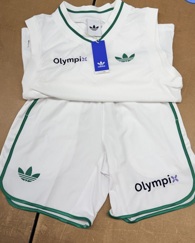 white Adidas performance apparel with green trim and multiple embroidered corporate logos
