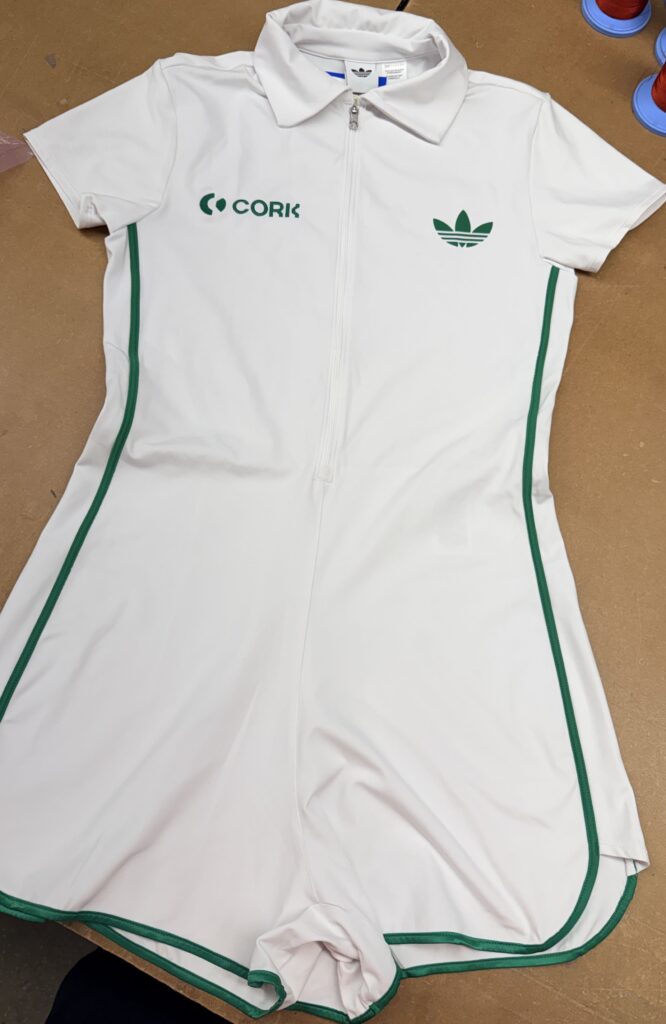 white Adidas performance apparel with green trim and multiple embroidered corporate logos