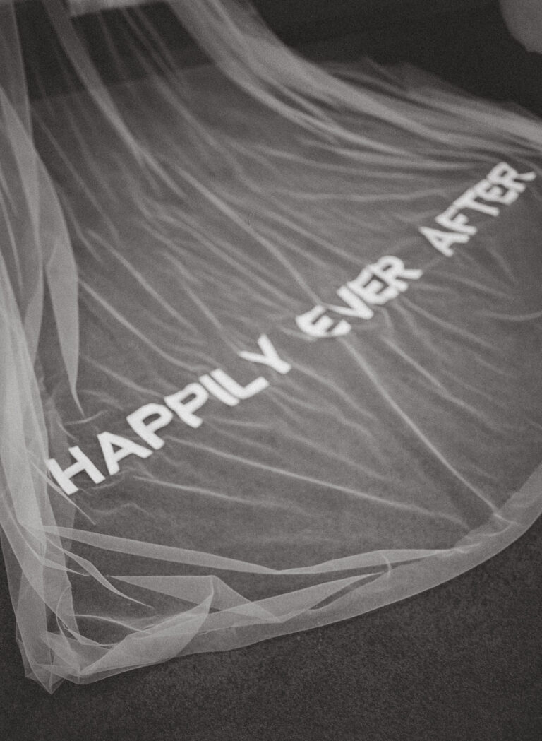 Custom embroidered bridal veil with “Happily Ever After” text laid out in studio workspace