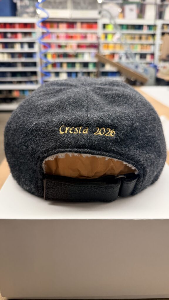 Back view of wool cap with gold embroidered text reading “Cresta 2026”