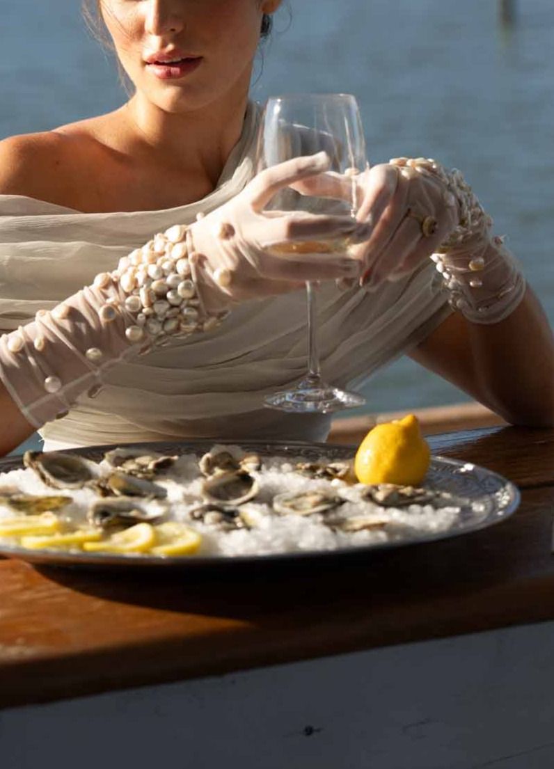 Sheer pearl embellished bridal gloves holding a cocktail glass during an editorial shoot
