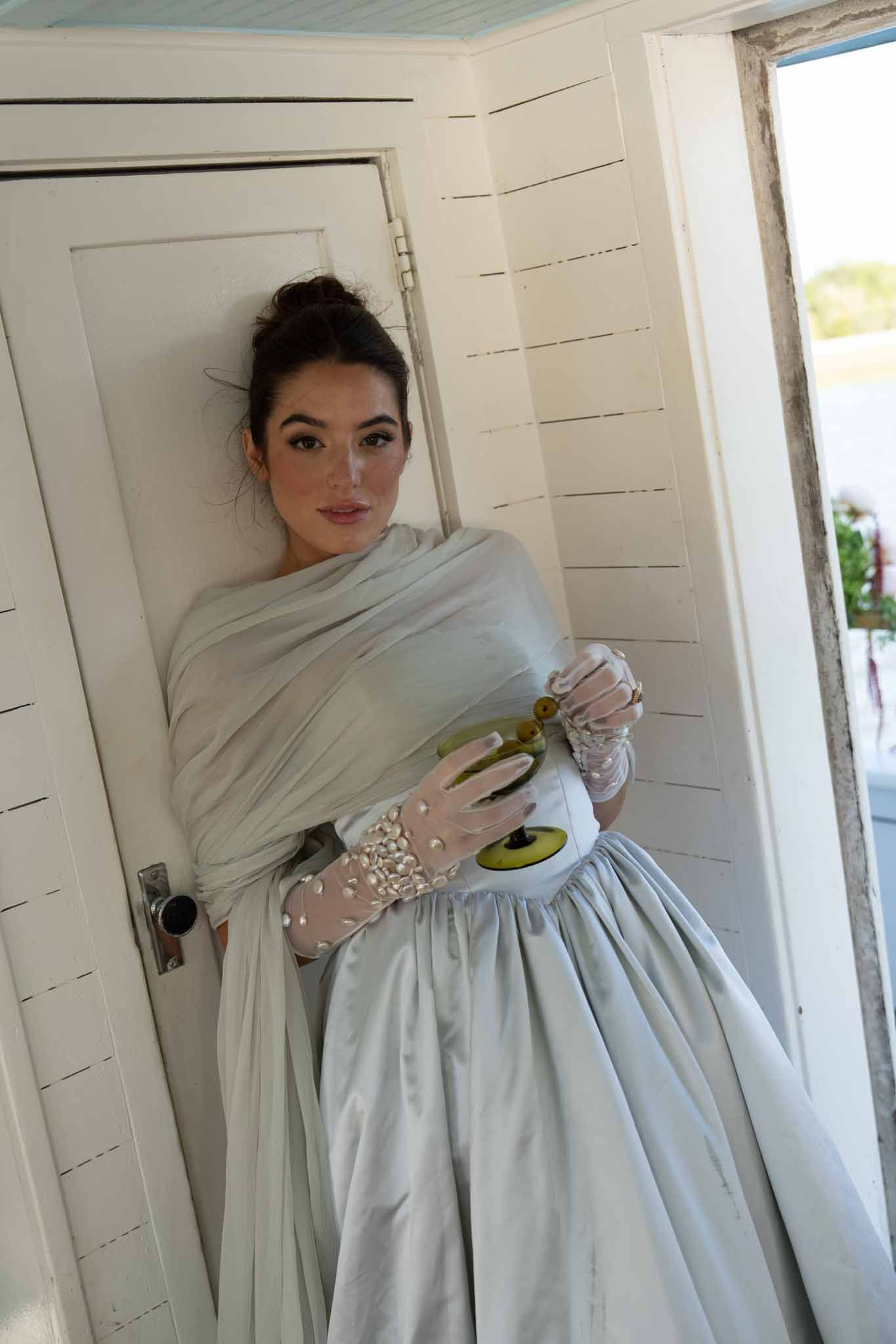 Sheer pearl embellished bridal gloves holding a cocktail glass during an editorial shoot