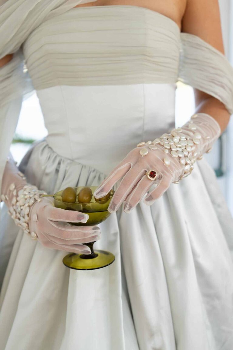 Sheer tulle bridal gloves hand-embellished with pearls, styled with a draped couture wedding gown