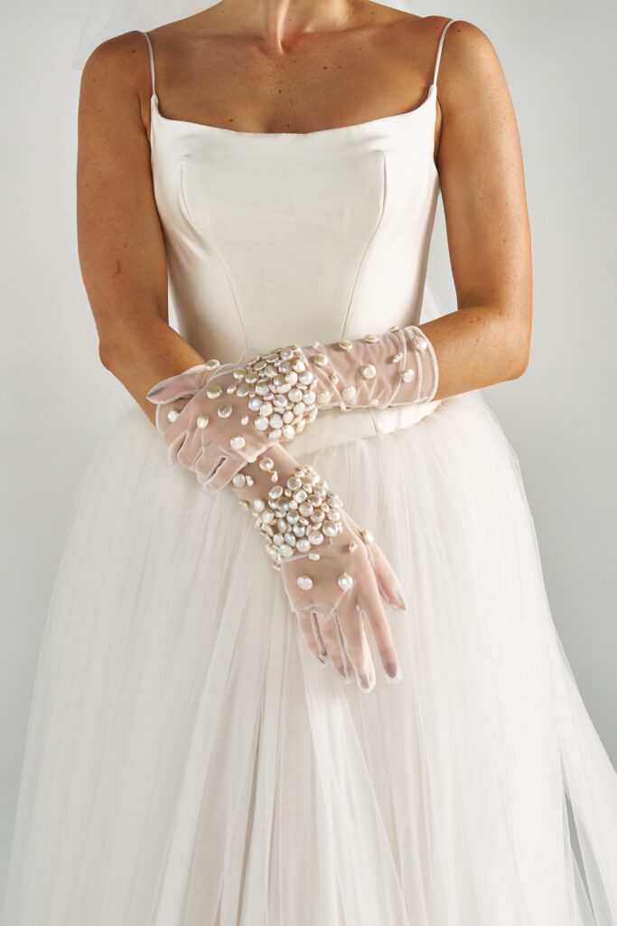 Close-up of hand-beaded pearls on sheer tulle bridal gloves