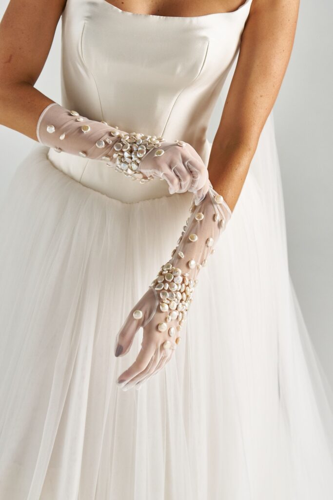Close-up of hand-beaded pearls on sheer tulle bridal gloves