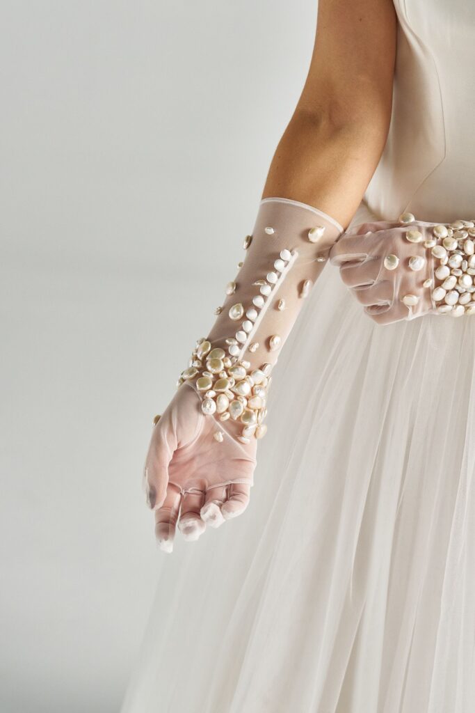 Close-up of hand-beaded pearls on sheer tulle bridal gloves