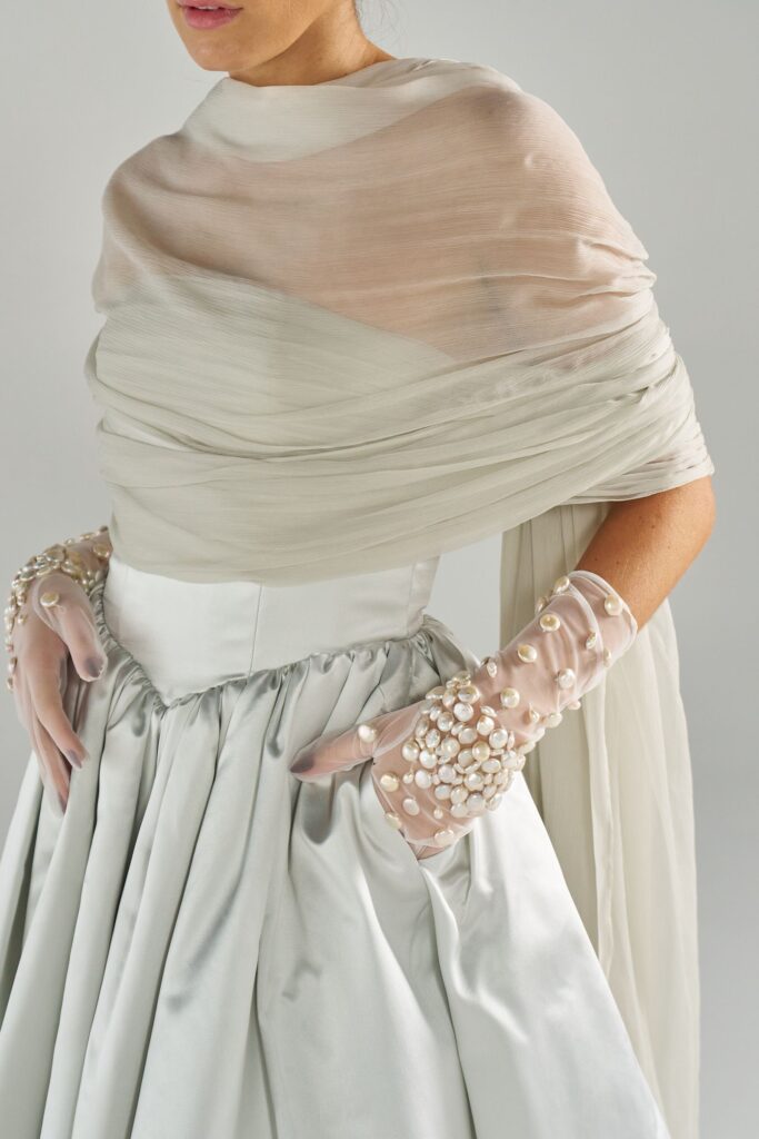 Side view of sheer tulle bridal gloves with pearl embellishment and flowing wedding skirt
