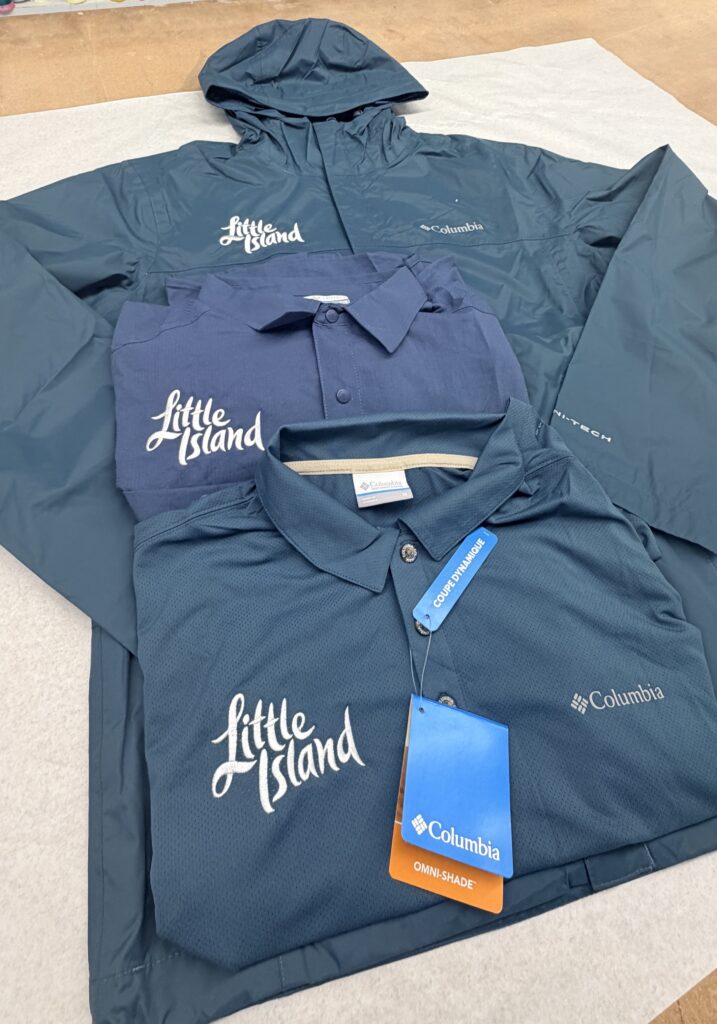 hite embroidered Little Island logo on teal and navy Columbia Sportswear performance uniforms for the brand's staff apparel refresh.