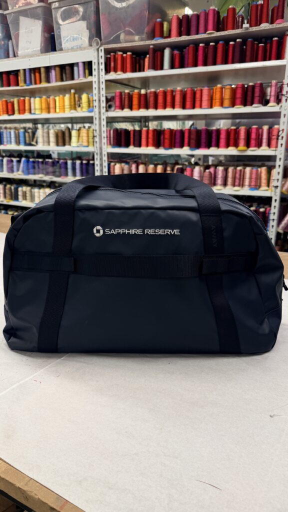 Custom corporate gift embroidery featuring the Chase Sapphire Reserve logo on Away duffle bags and L.L.Bean canvas totes.