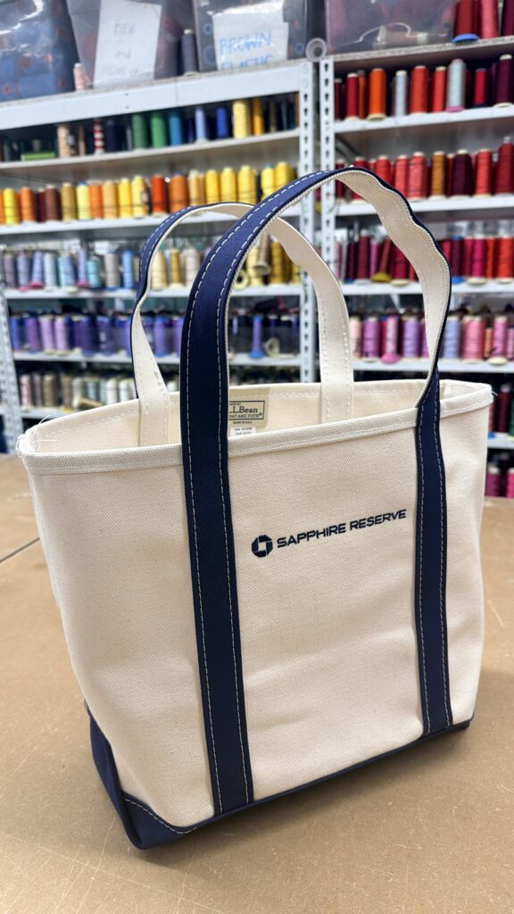 Custom corporate gift embroidery featuring the Chase Sapphire Reserve logo on Away duffle bags and L.L.Bean canvas totes.