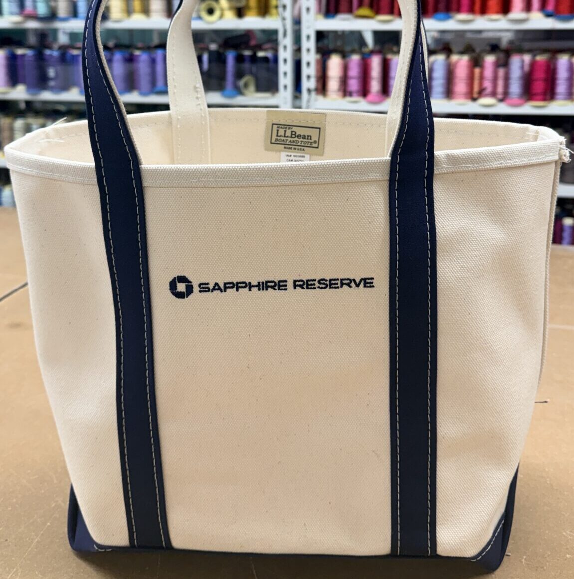 Custom corporate gift embroidery featuring the Chase Sapphire Reserve logo on Away duffle bags and L.L.Bean canvas totes.