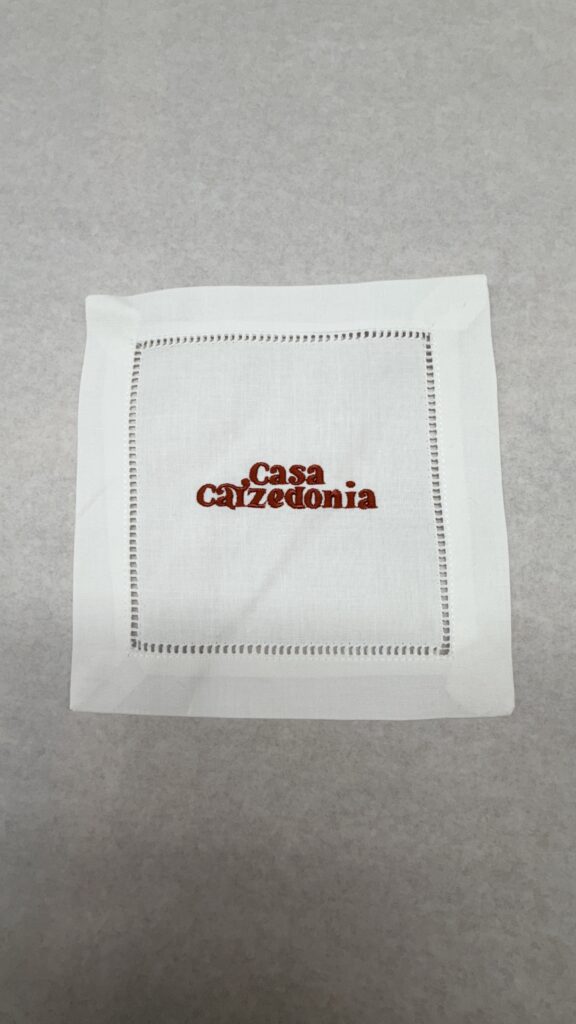 Close-up of detailed embroidery on branded linen napkins for luxury beachside event