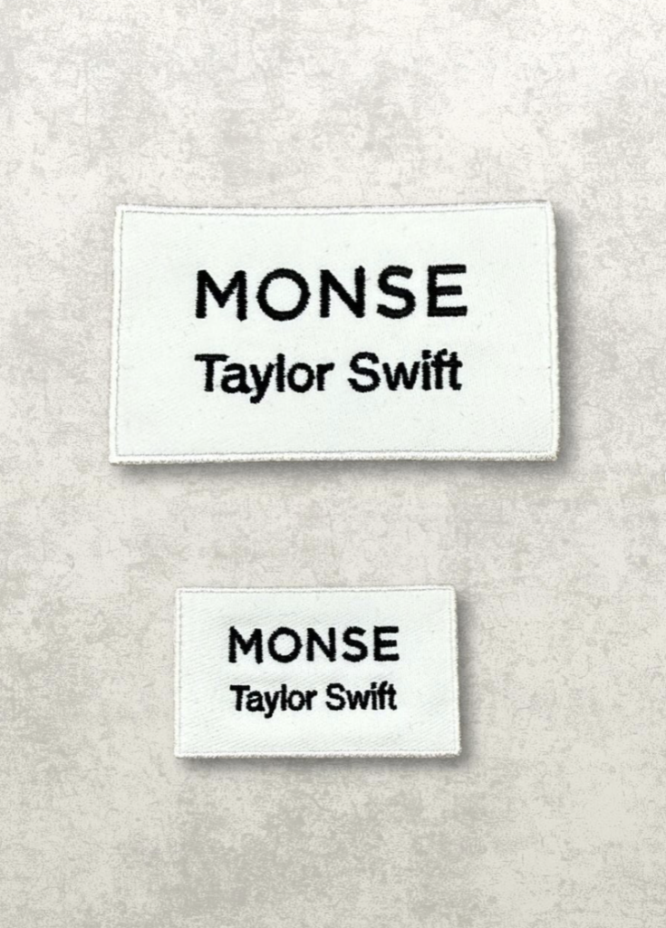Two white embroidered custom clothing labels featuring black text reading Monse and Taylor Swift on a textured beige background.