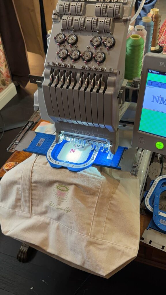 Guest customizing a tote bag at NYES live embroidery event at Velvet Caviar Cafe