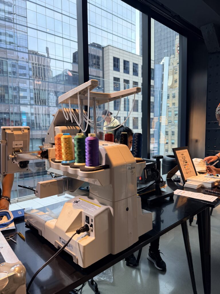 Live embroidery and heat press customization station creating personalized Pride bucket hats and bandanas during the One Times Square Pride celebration.