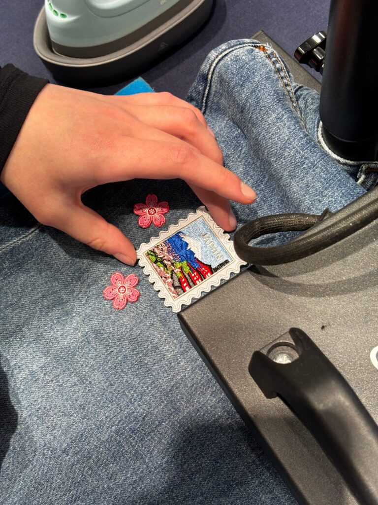 Guest customizing newly purchased GU denim with live embroidery and heat press patches during an interactive in-store activation.
