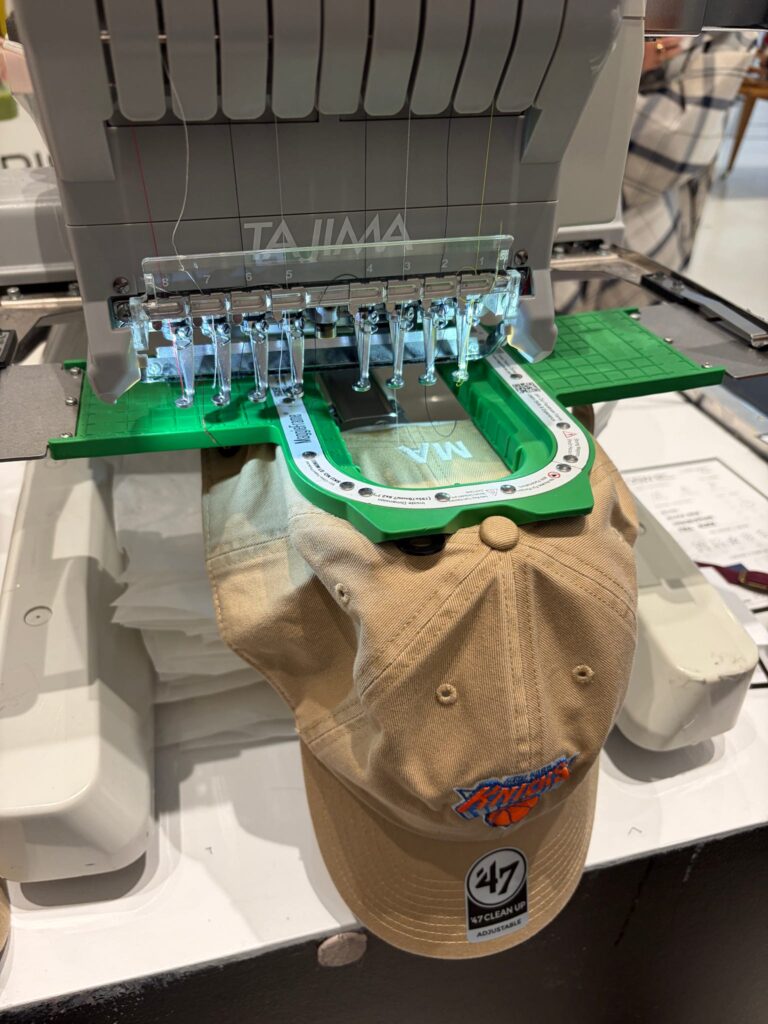 Hat being personalized with live embroidery at a DSW event